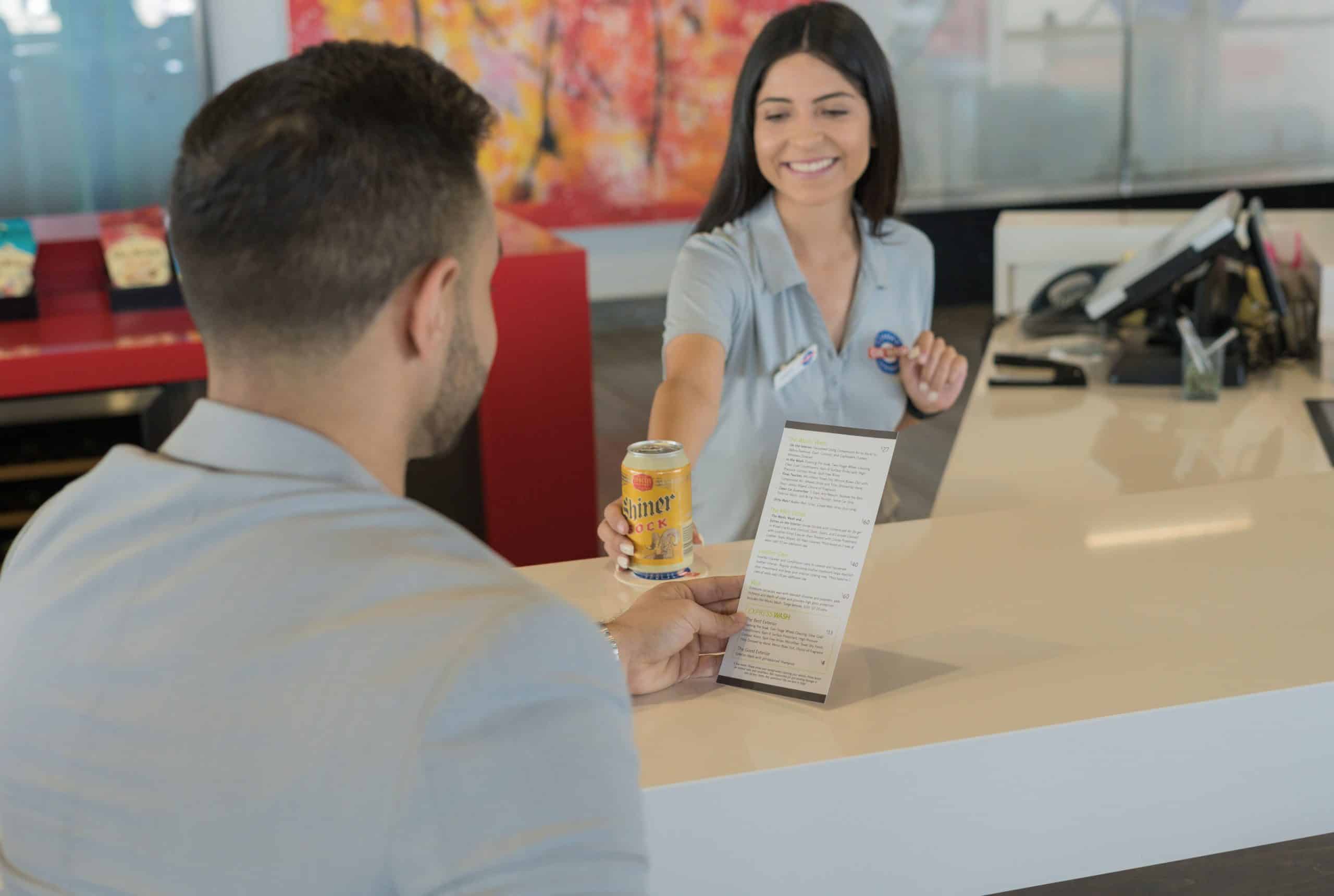 A man and woman interacting at a hotel counter, engaged in a conversation about their stay.