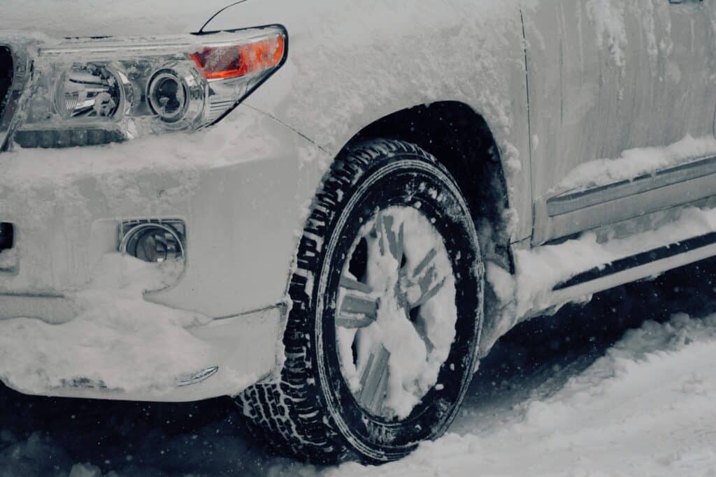 A white SUV completely covered in a thick layer of snow, showcasing a winter landscape.