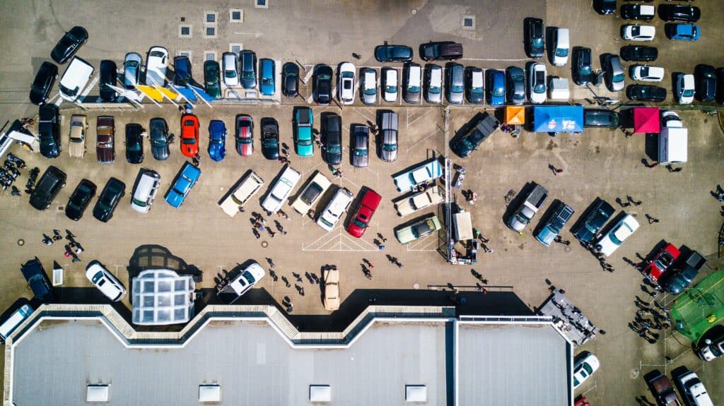 Aerial view of a parking lot filled with numerous cars, showcasing organized rows and various colors of vehicles.