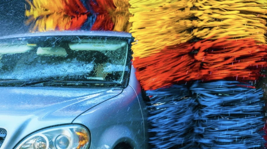 A car is being cleaned with a large brush, showcasing the washing process in action.