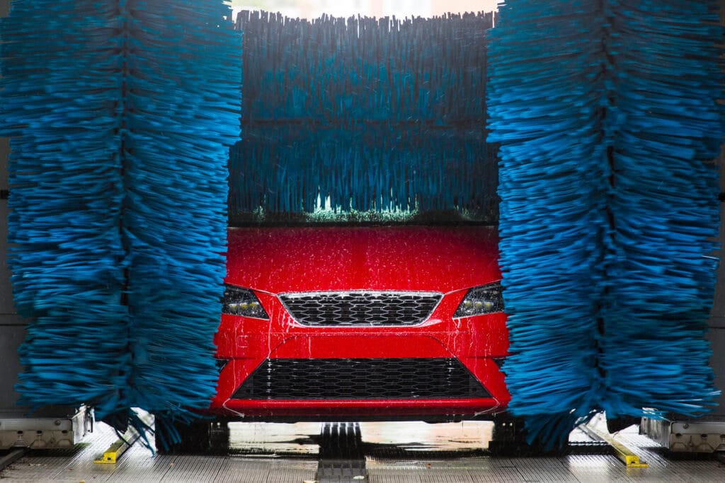 A woman diligently cleans the windshield of a car, ensuring clear visibility for safe driving.