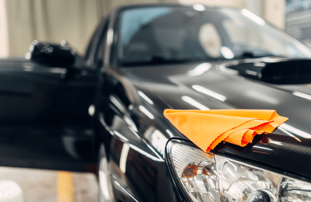 A car parked with a towel draped over its hood, showcasing a casual and relaxed atmosphere.